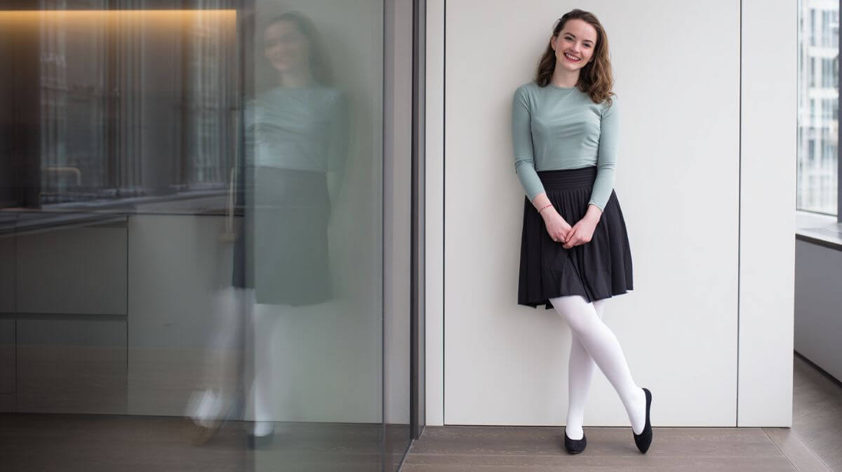 young woman in office wearing ballet flats with white tights and skirt